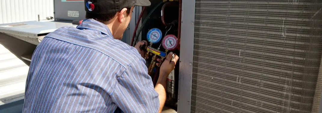 HVAC technician servicing a condenser unit in Sparks